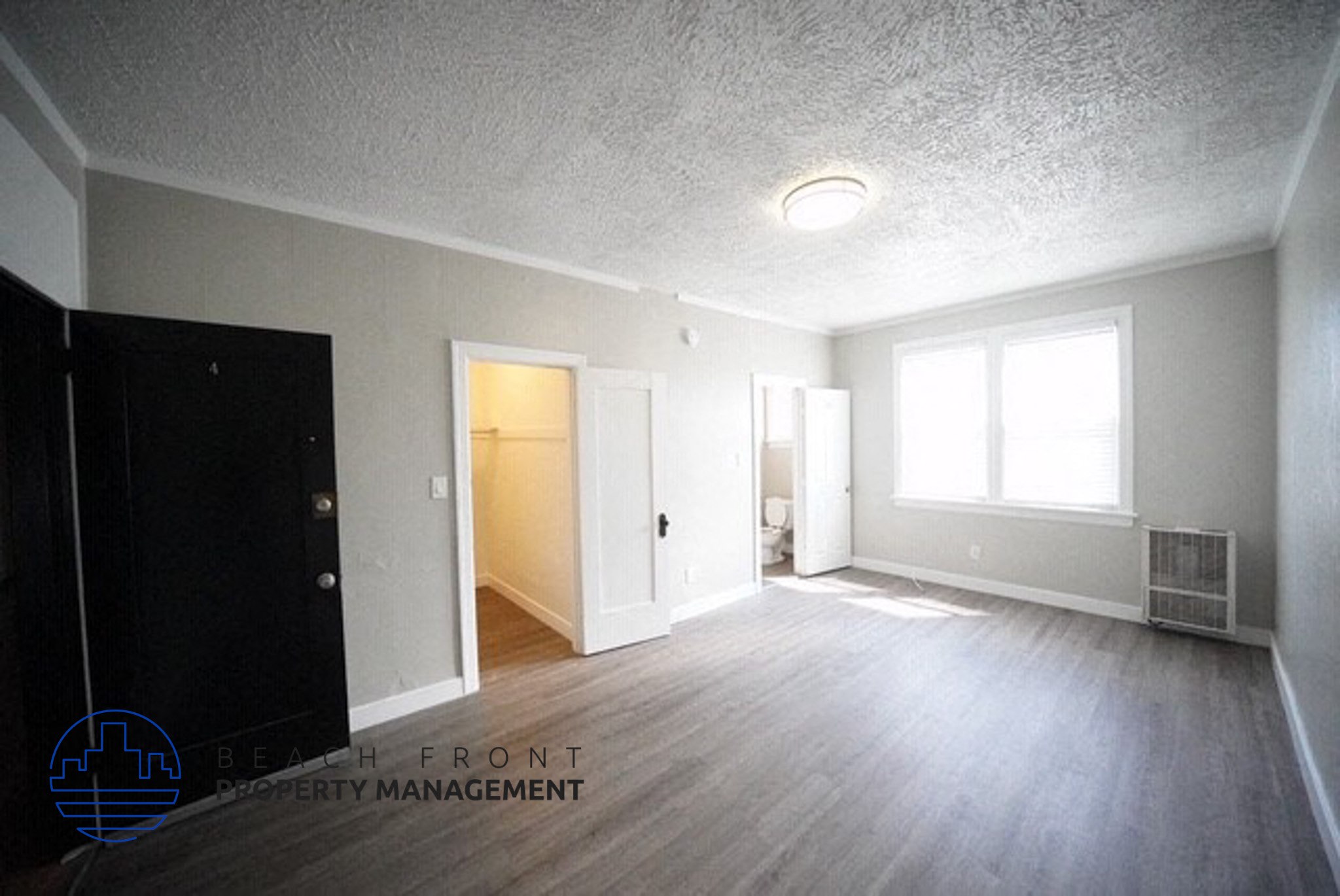 an empty living room with wood floors and a black door